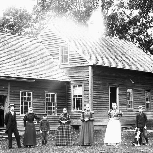 adults and children standing in front of house