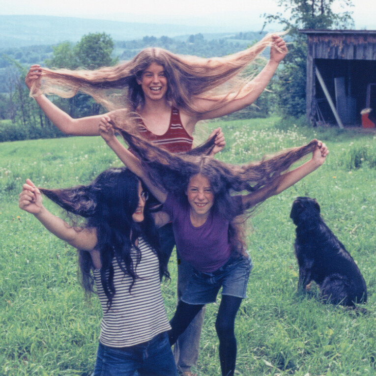 Three girls holding out their long hair
