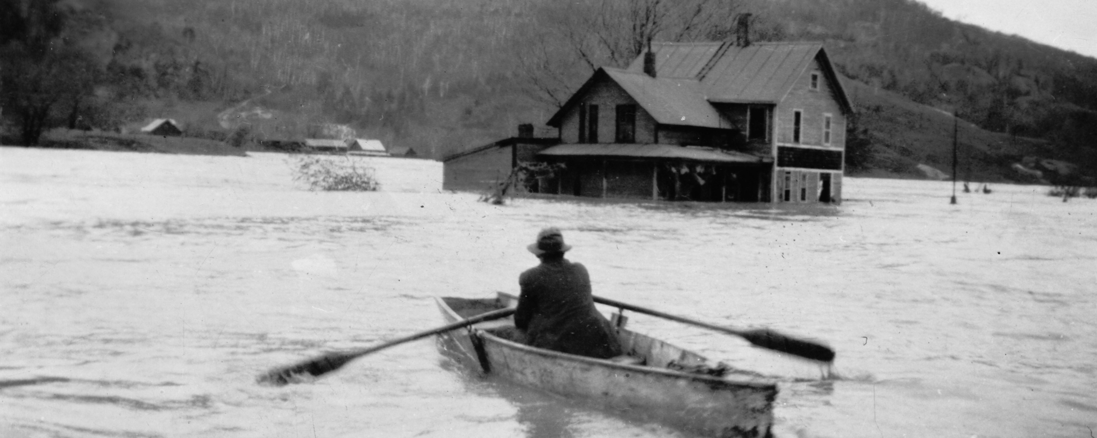 man in row boat by flooded house