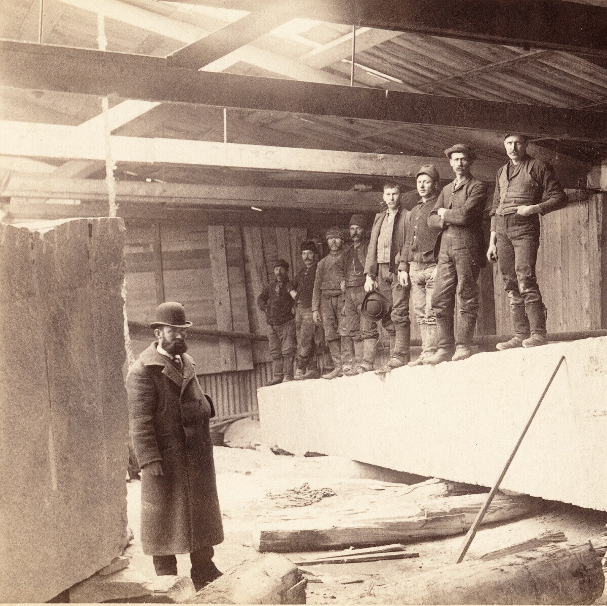 old photo of men standing on granite in warehouse