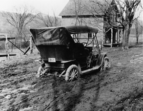old photo of car stuck in deep mud