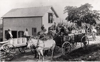 old photo of milk cans in cart with men