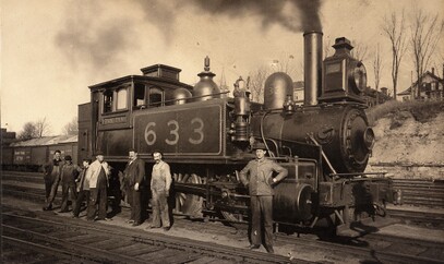 old photo of men standing by locomotive engine