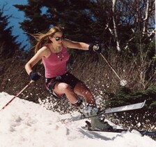 woman skiing in tank top, shorts, & sunglasses