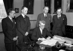George Aiken signing legislation with men looking on