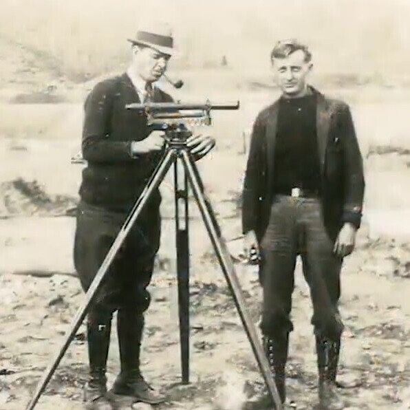 old photo of two men surveying